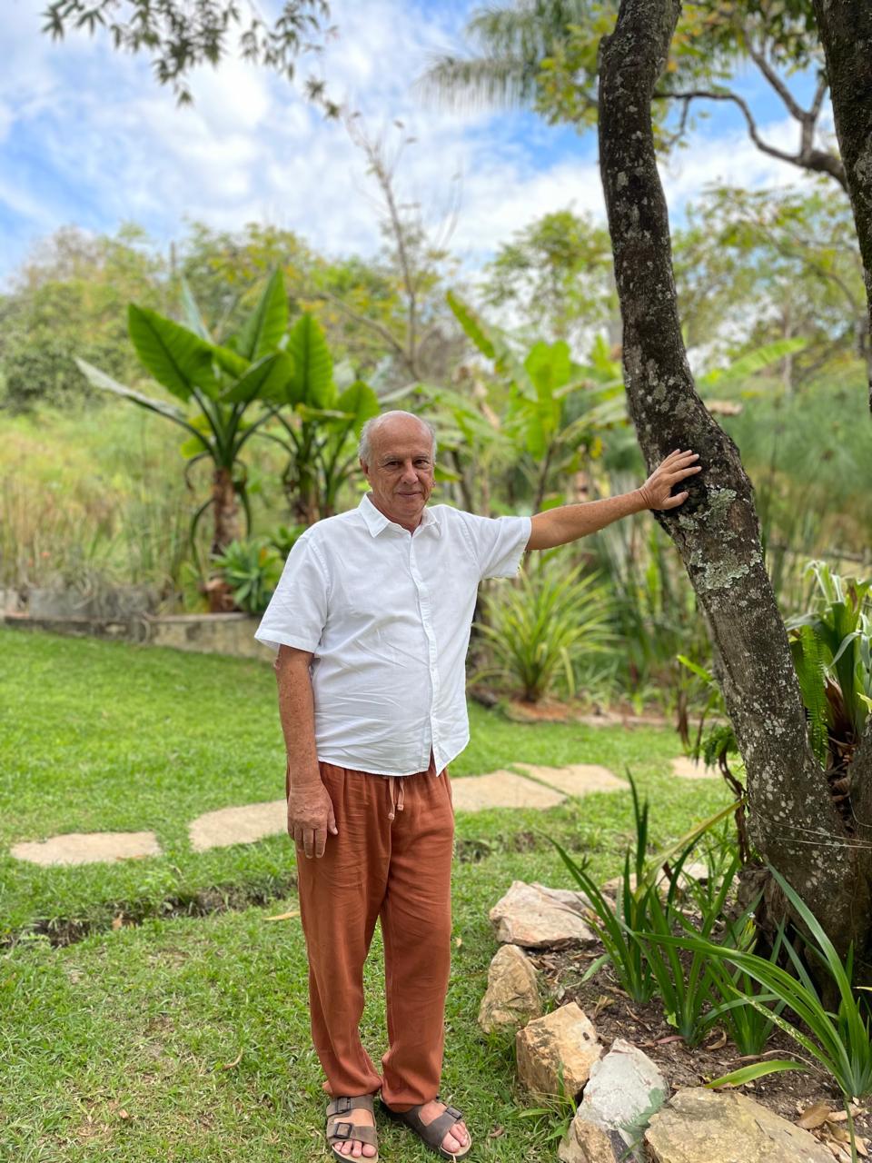 Pete Coe em um jardim, ao lado de uma árvore, em ambiente natural